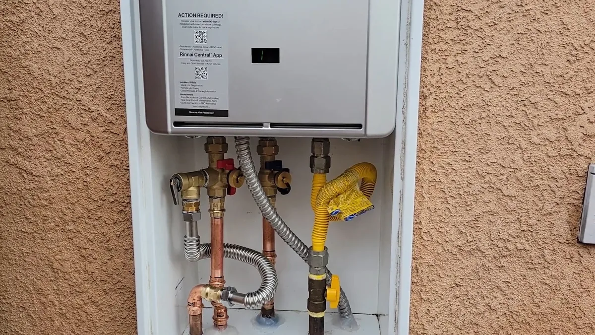 Tankless water heater mounted in a recess in a stucco exterior wall