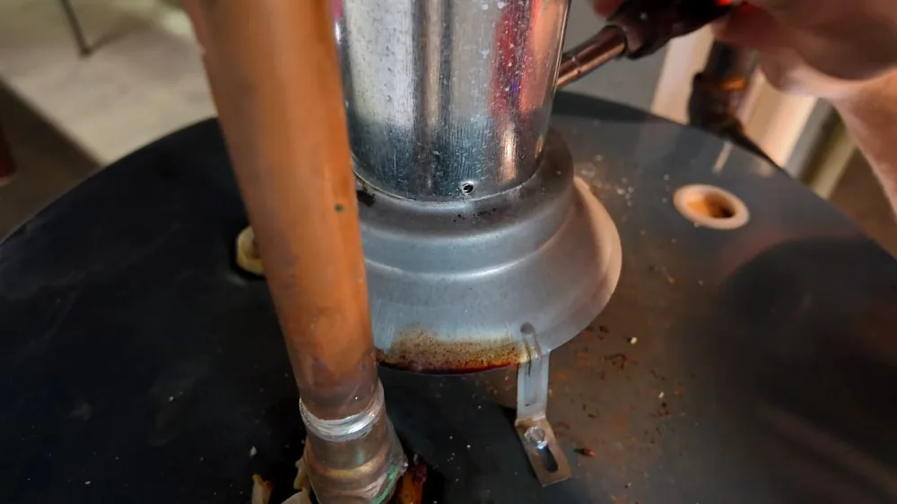 Metal vent pipe and copper supply lines rising from the top of a water heater